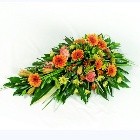 Orange and yellow funeral spray with germini, chrysanthemums, roses, and carnations.